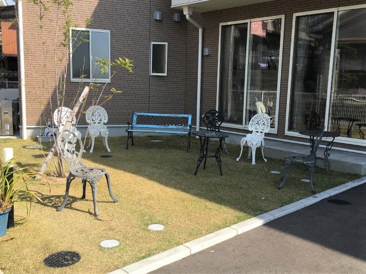 白や黒のガーデン用の椅子やベンチが並べられた庭には遊歩道があり、段差もなく、木が植えられている。日当たりのいい場所と影になっている場所がある。