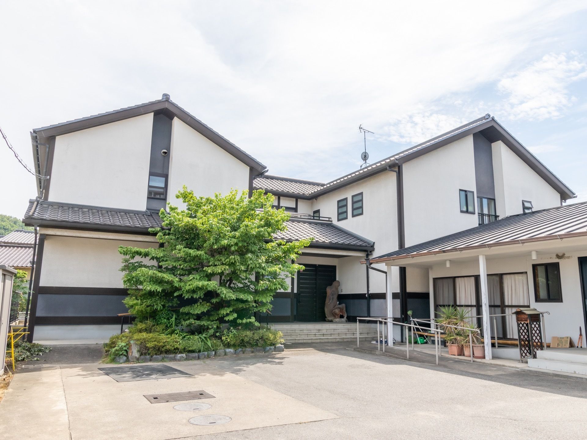 おしゃれな和風の2階建ての建物である。建物の近くには木が植えられており、その前には広いスペースがある。
