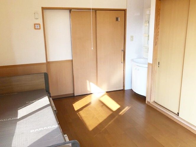 大きな収納スペースが付いたフローリングの部屋には介護ベッドや洗面所があり、出入り口はスライド式。