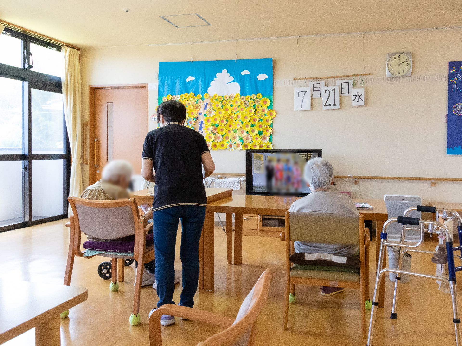 テレビが設置され、入居者とスタッフが会話をしているリビング
