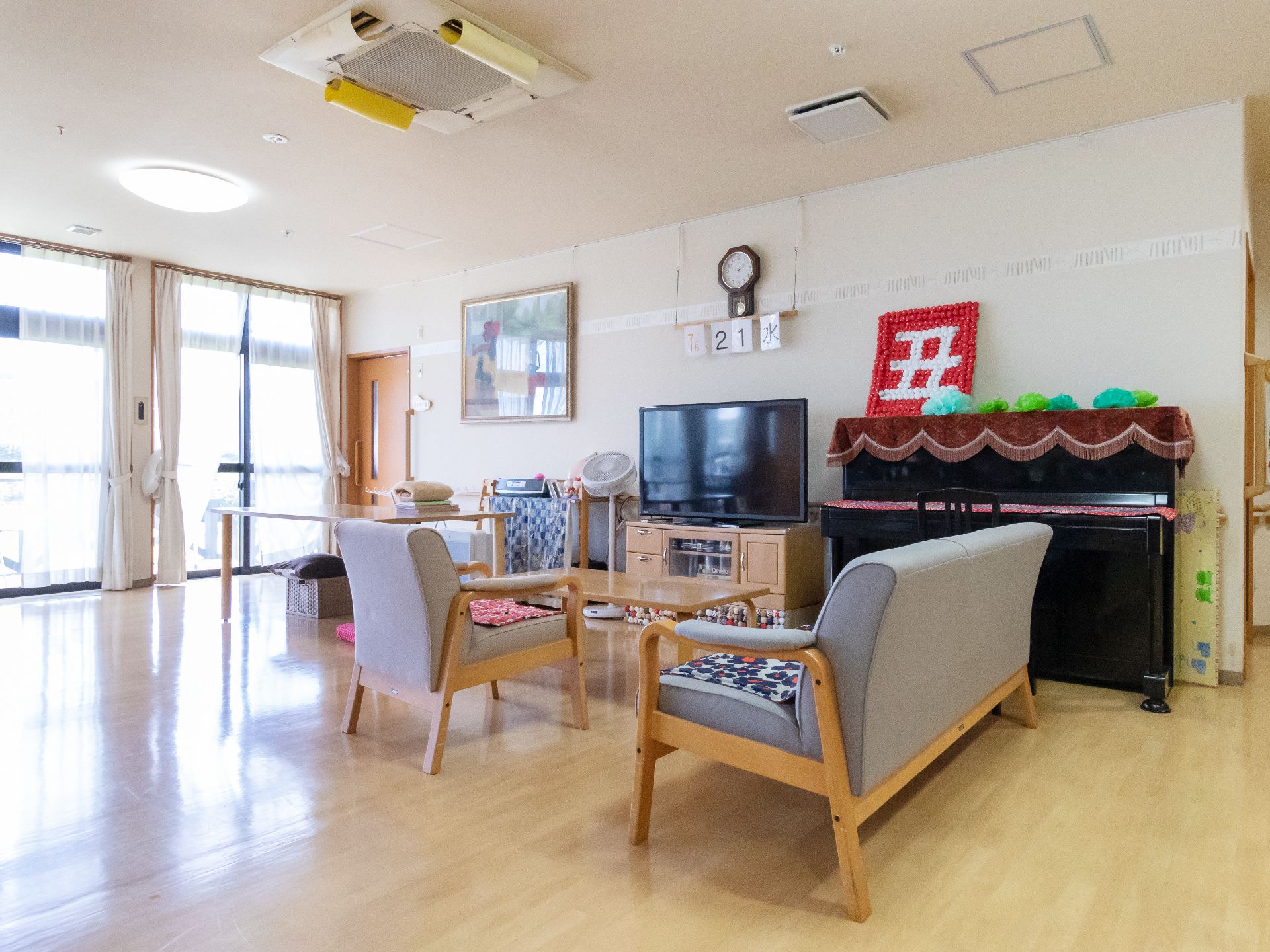 大きなテレビ、テーブル、椅子、ピアノなどが置かれているリビング