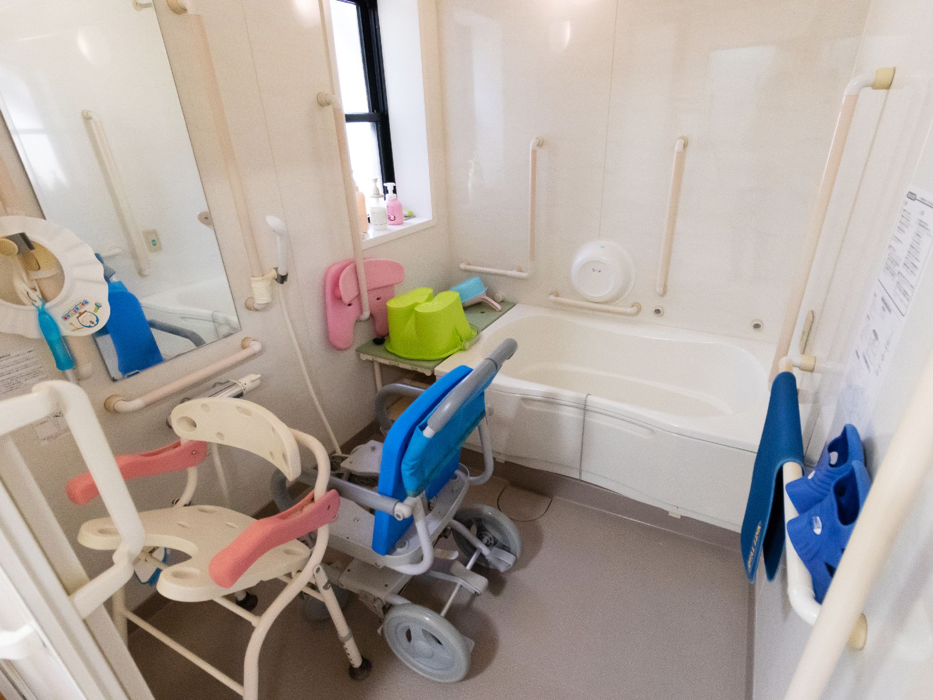多数の手すりが取り付けられ、シャワーチェアが置かれている浴室