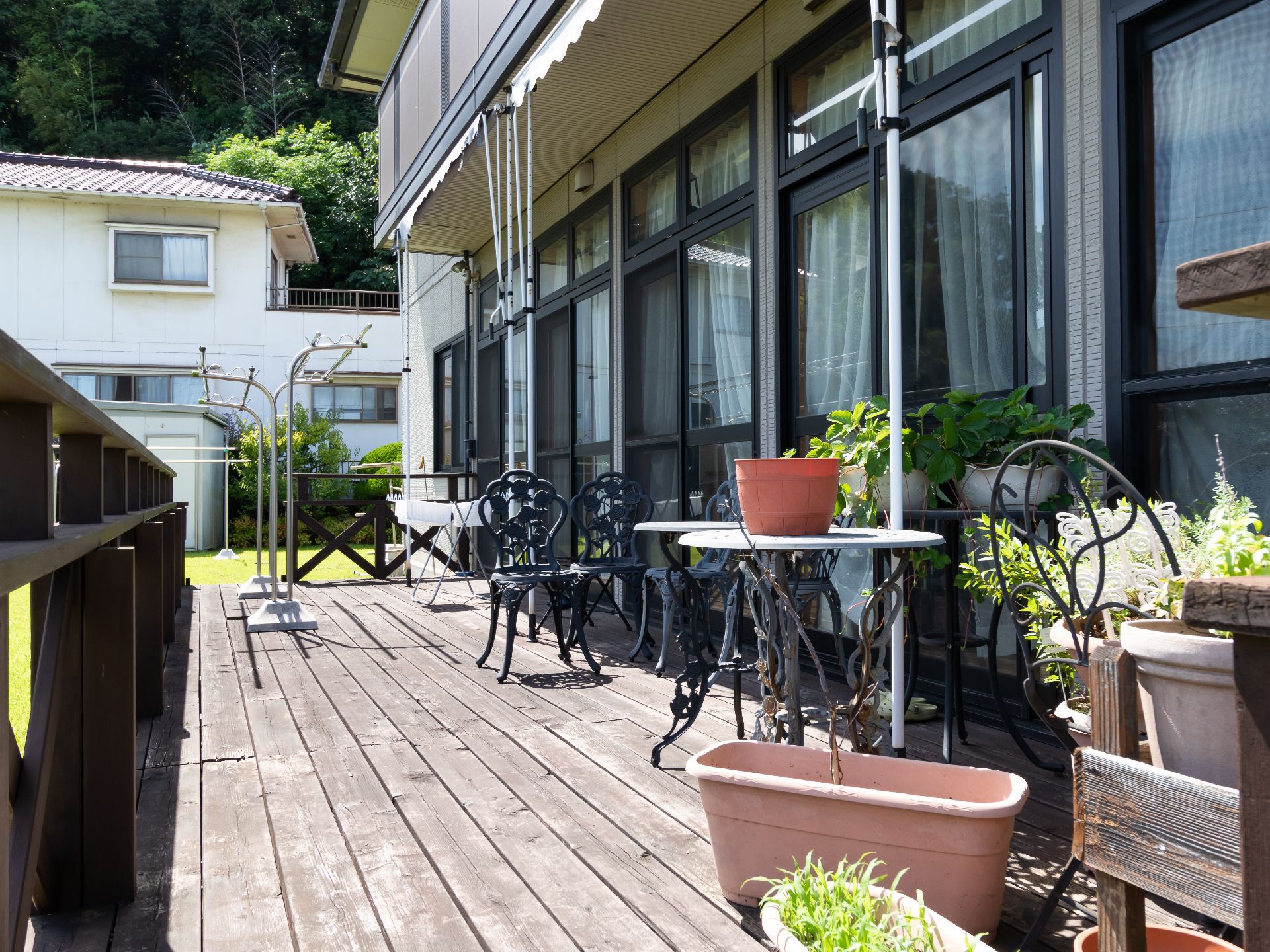 日の光が降り注いでいる、植木鉢が置かれたウッドデッキ