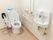 壁にL字型手すりと呼び出しブザーが設置されたトイレである。温水洗浄便座器をはさみ、可動式手すりが降ろされている。