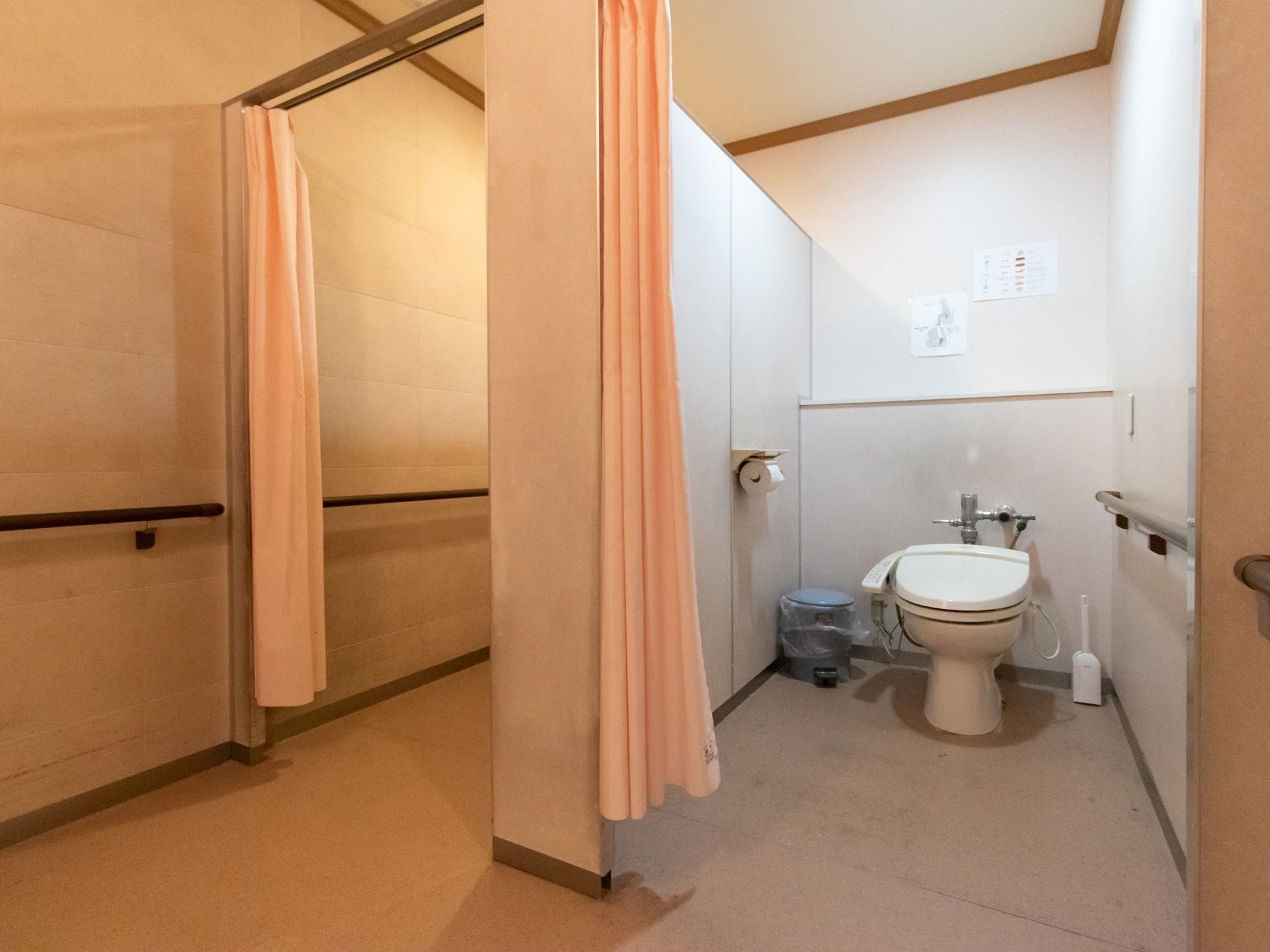 個室のドアの代わりに、カーテンがかけられているトイレである。床にはふた付きのゴミ箱が置かれており、壁には手すりがある。