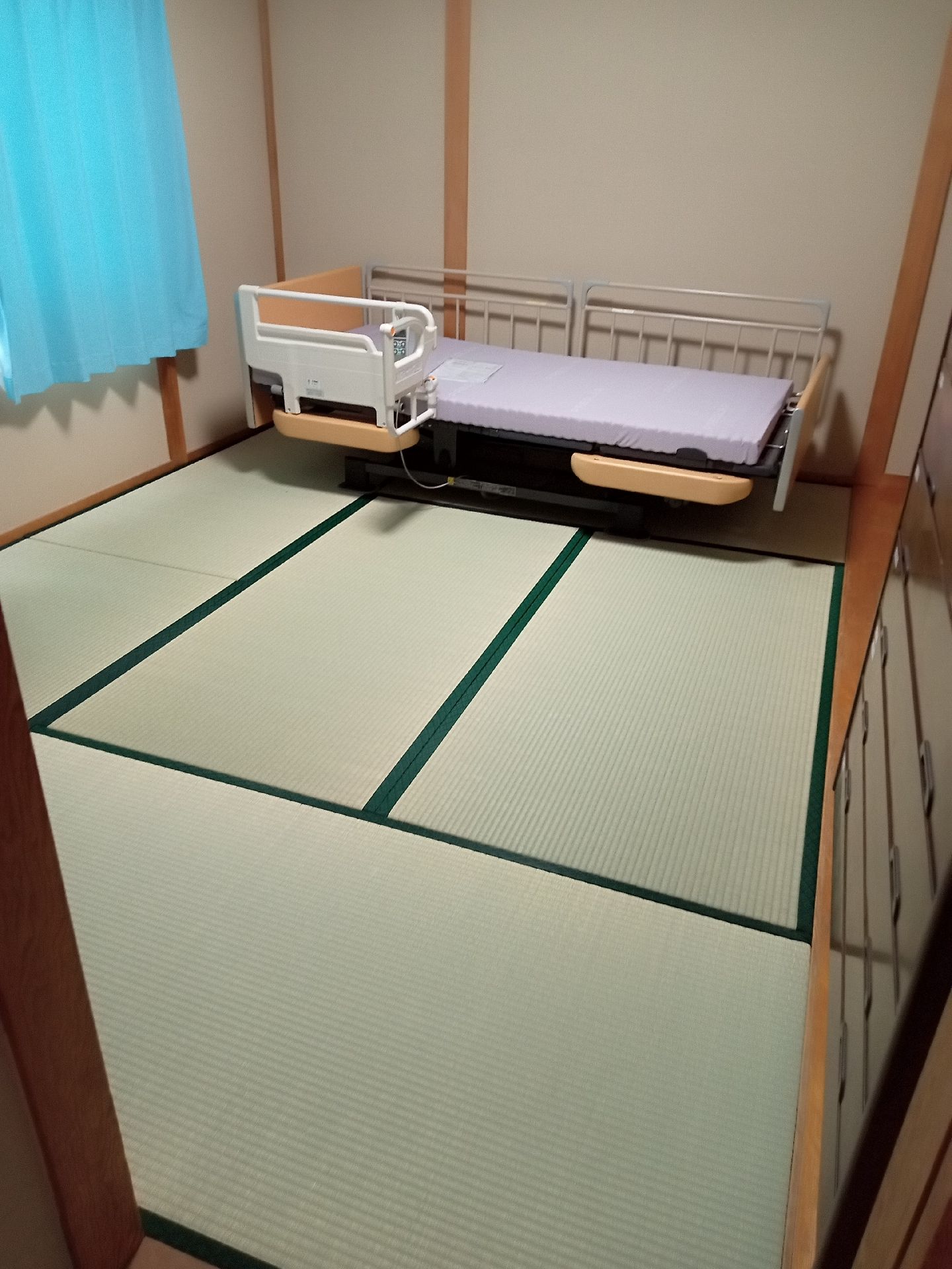 ベッドがひとつだけ置かれている畳の和室の様子。施設の居室の写真