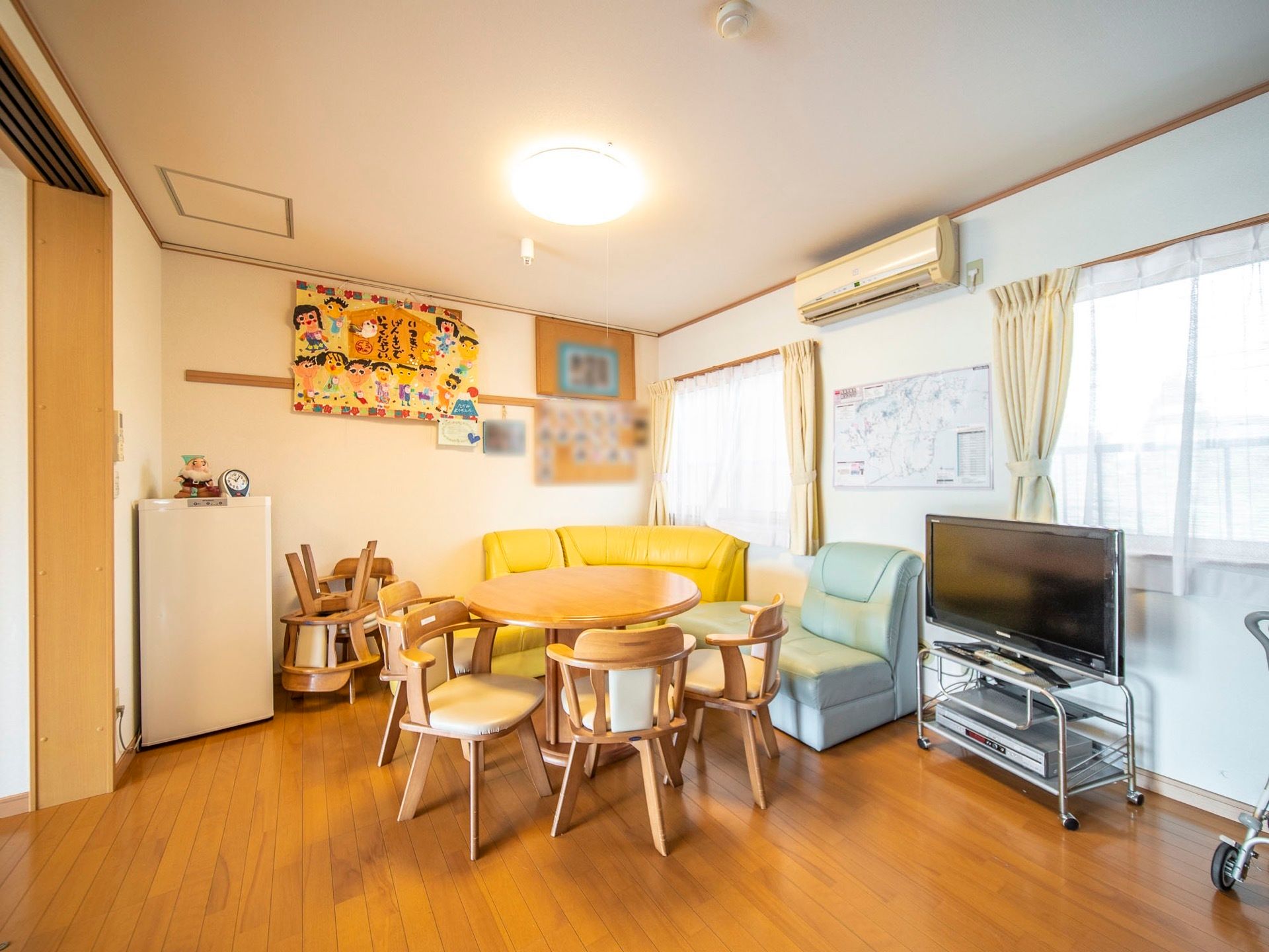 円形のテーブルにソファーや座面が回転式の椅子が配置された談話室である。壁には、かわいらしい作品がレイアウトされている。