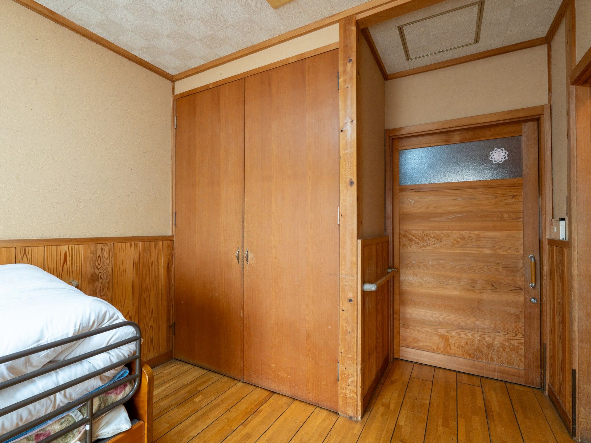 木製の扉とベッドの部屋