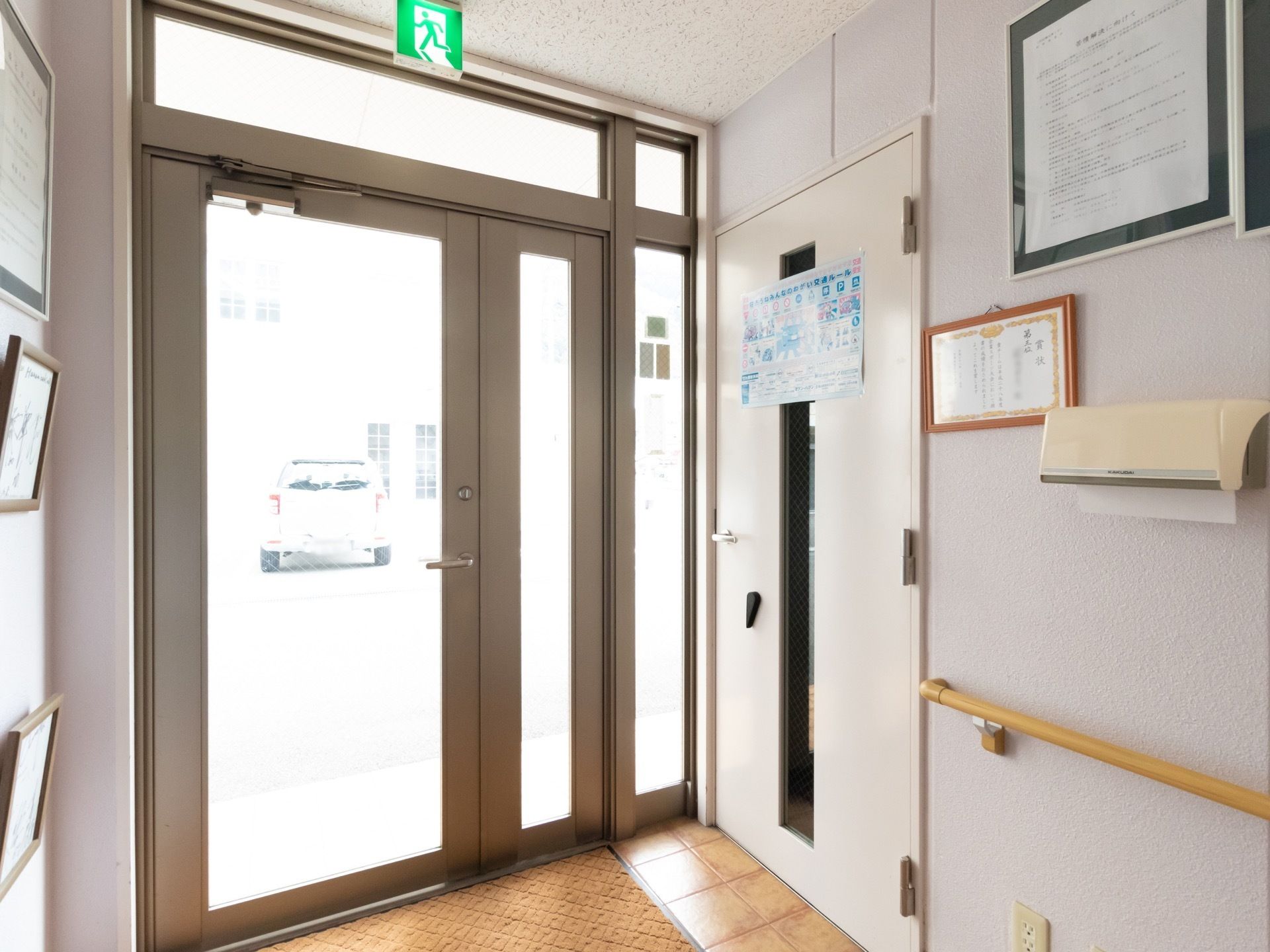 玄関はガラス張りの扉になっており、外からの光が差し込んでいる。壁には手すりが取り付けられている。ペーパータオルも完備。