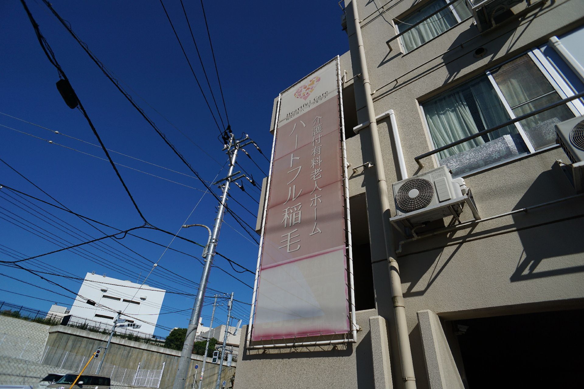 白い建物の横についたピンク色の看板