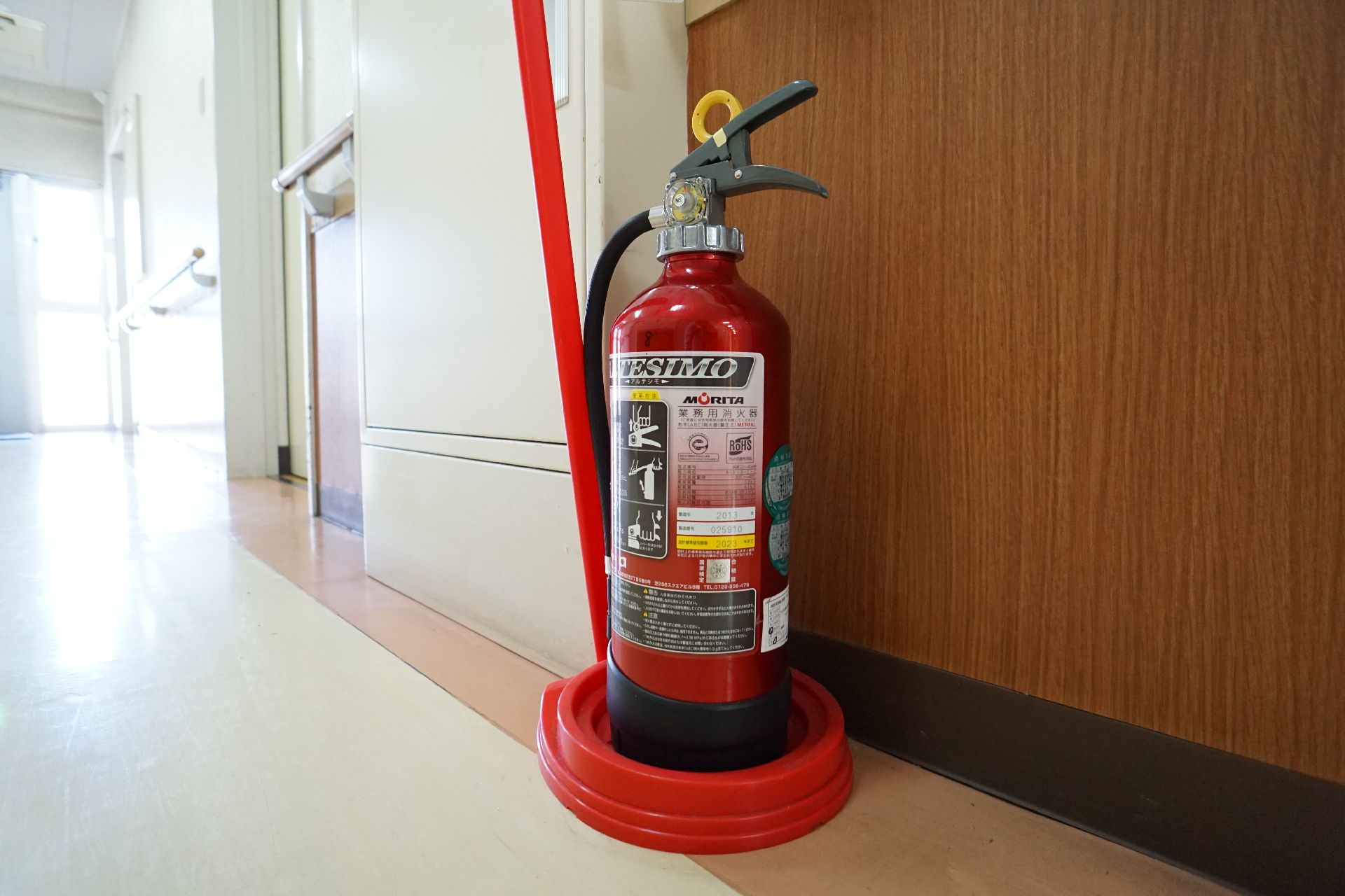 白い壁の廊下に配置された消火器