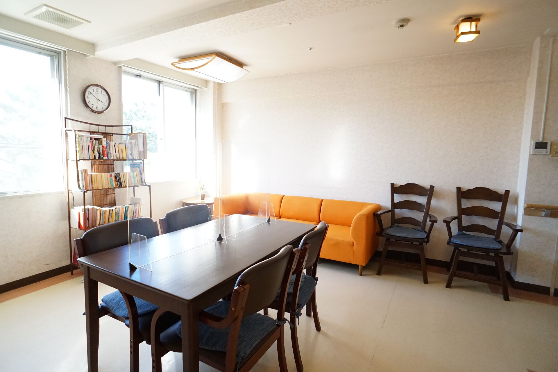 白い壁の部屋に置かれた透明な仕切りが付いた木製の机