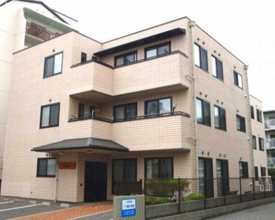 ベージュを基調としたオシャレな外壁。駐車場が隣接している。