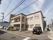 角地に建っている二階建ての建物がある。建物に沿って周囲は駐車場になっている。２階には大きなベランダと、１階部分にはウッドデッキがある。