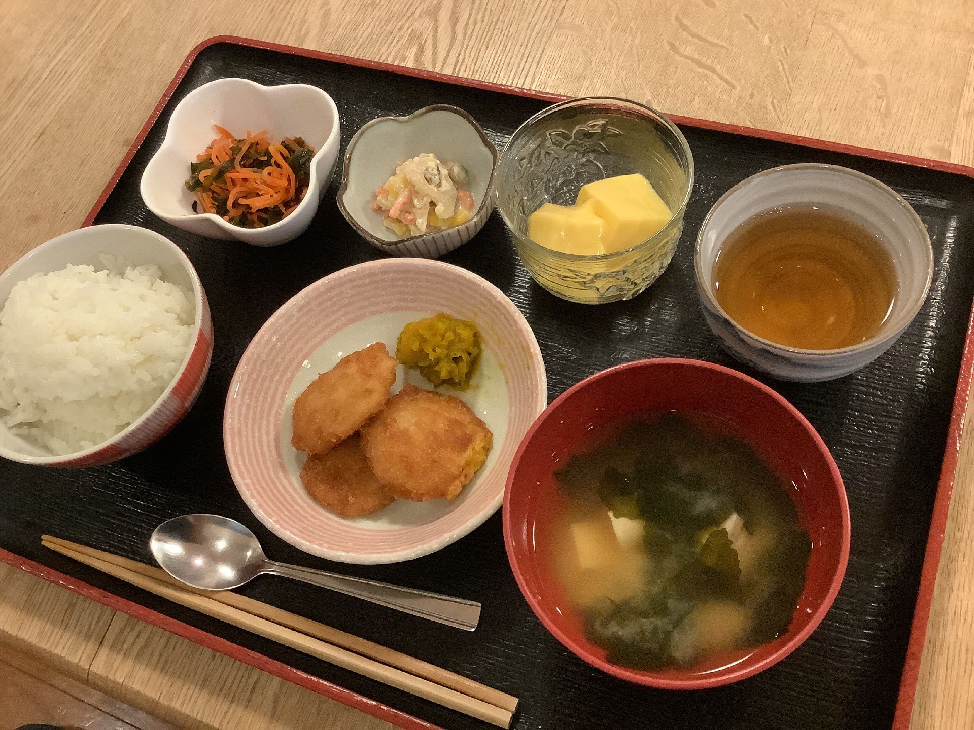 子×がたくさん並んでいる黒いトレーには白いご飯とみそ汁もあり、メインは揚げ物料理。