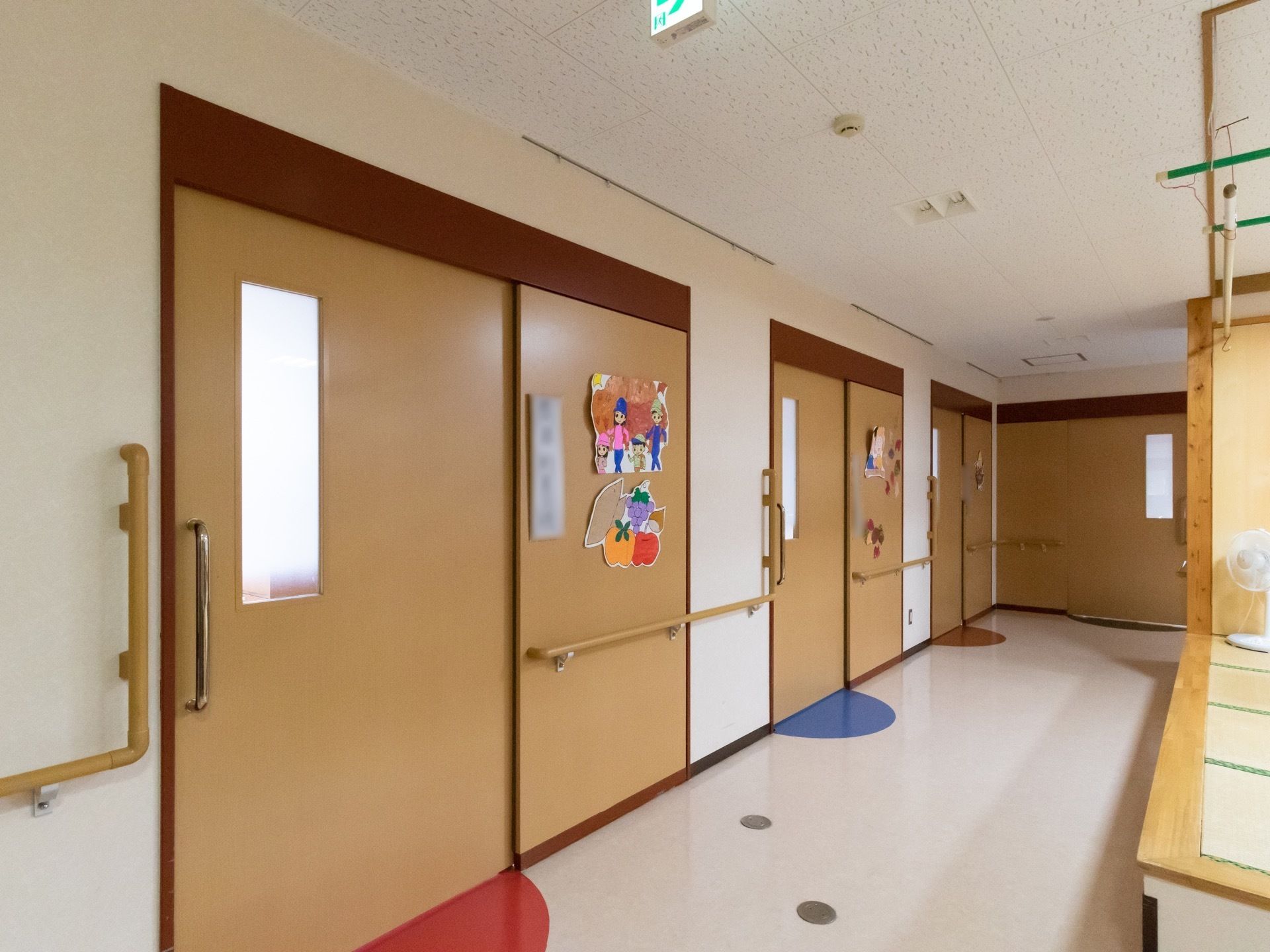 居室前の廊下には、間口の広い居室扉が設置されている。スライド式になっており、扉前の足元には半円のシールが貼られている。