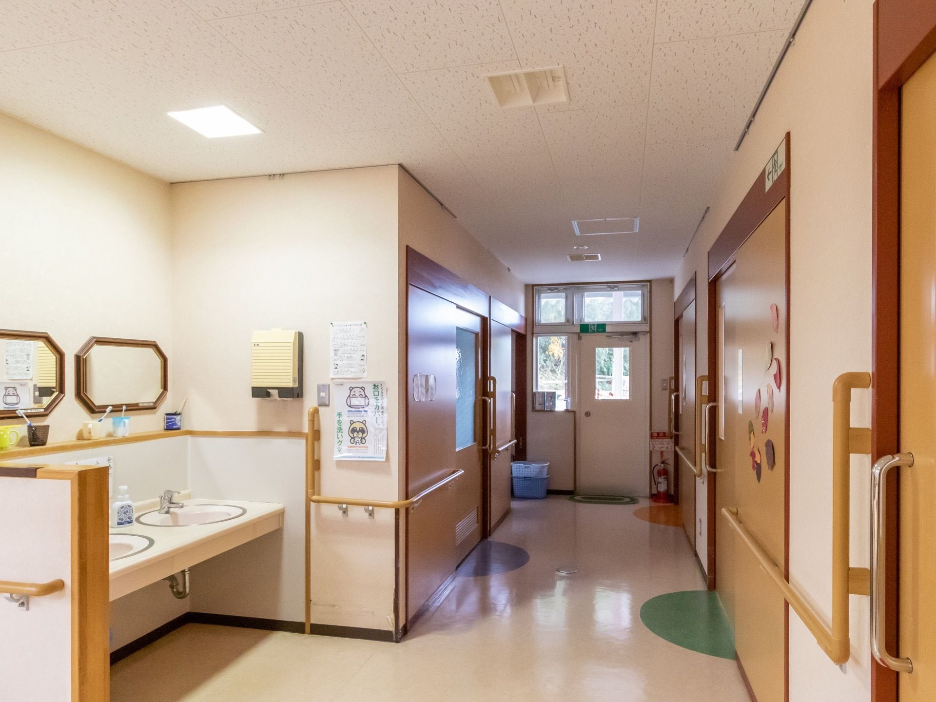 L字型手すりが壁伝いに設置されている廊下である。2連結の洗面台が完備され、それぞれに鏡が設けられている。