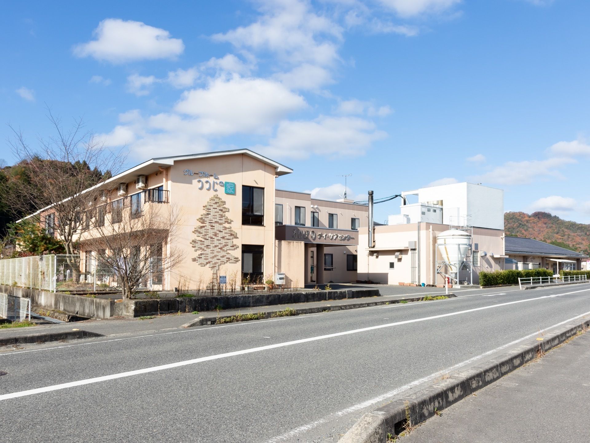 ホームとデイケアセンターなどが同じ通りに並んで建っている。建物の奥には木々が生い茂っているのが見える。