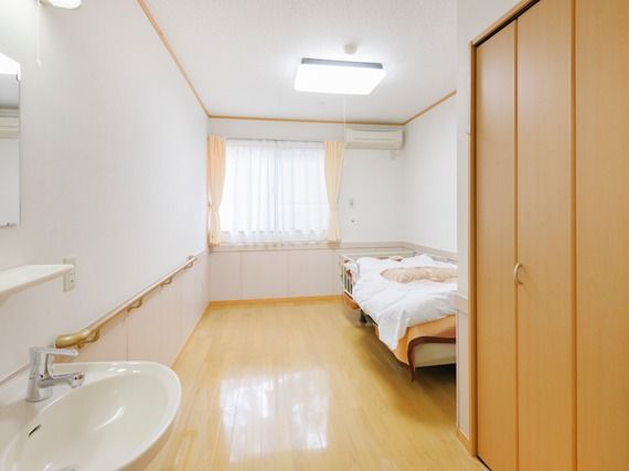 洗面所付きのフローリングの居室はエアコンやベッド、収納が設置されている。