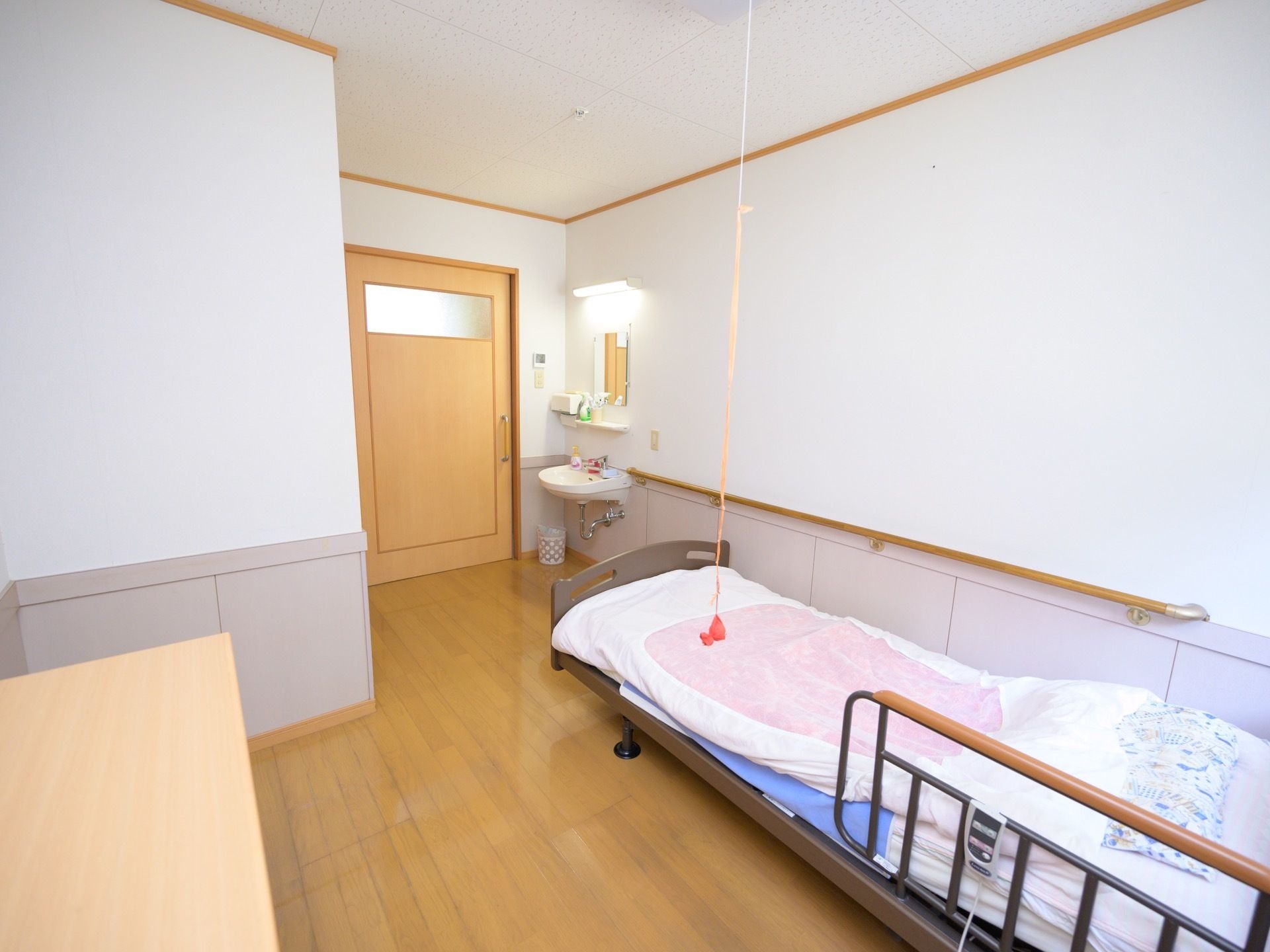 洗面台が備え付けられているワンルームの居室である。壁沿いにはリモコンで操作可能なベッドがある。