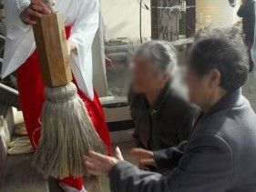 初詣で神社を訪れ、鐘を鳴らそうとしている女性スタッフ２名と手伝っている巫女。