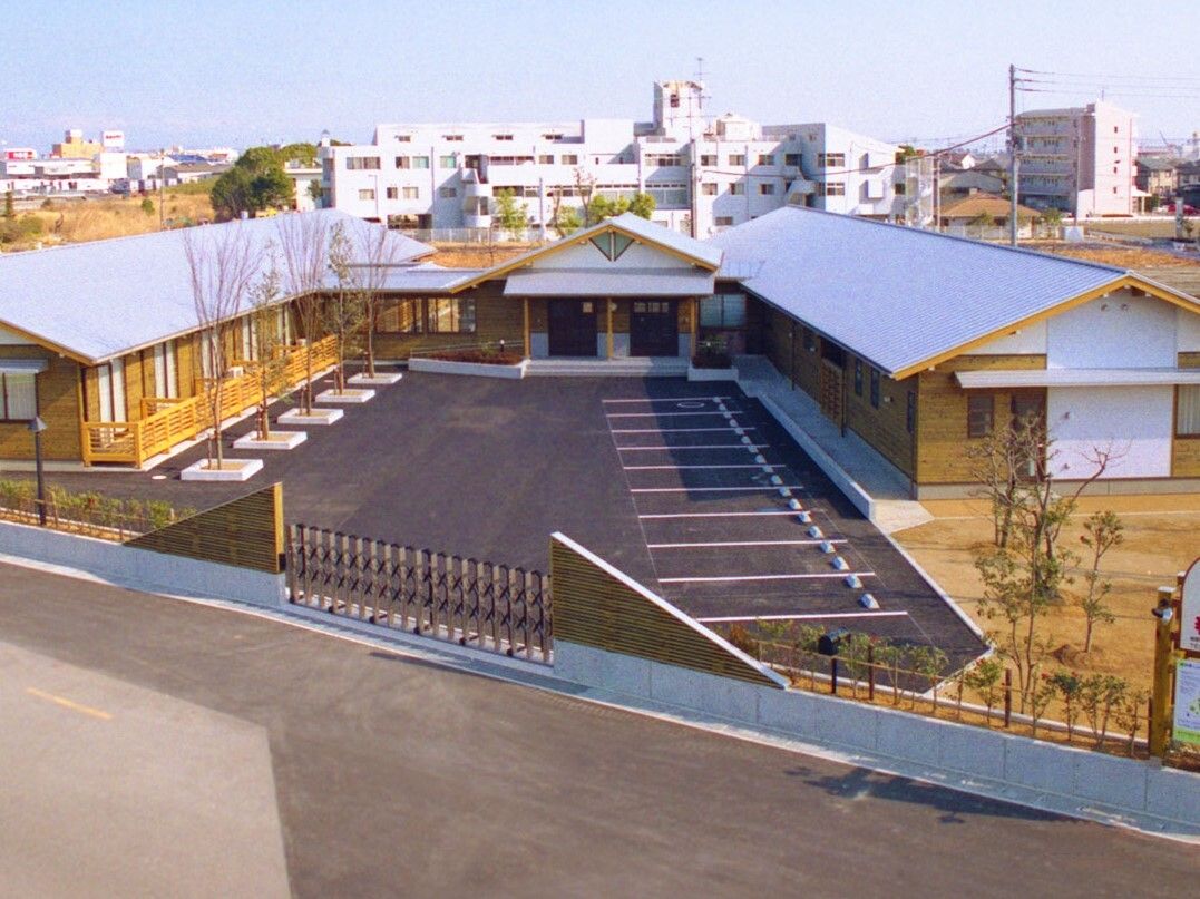 広い駐車場を囲むようにコの字の平屋建ての建物が設置されている。敷地内には木も植えられ、日当たり良好。