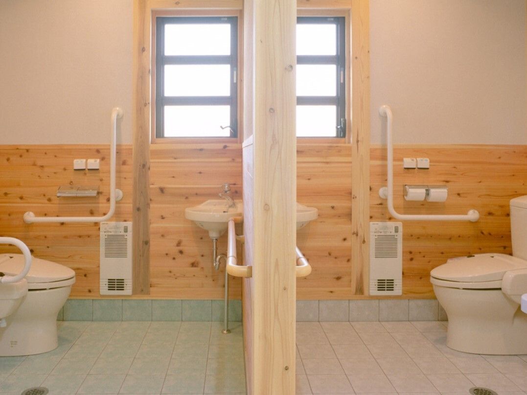 エル字型の手すりや呼び出しボタンが付いた２つのトイレは左右対称のデザイン。トイレ内は広く、手洗い場も付いている。