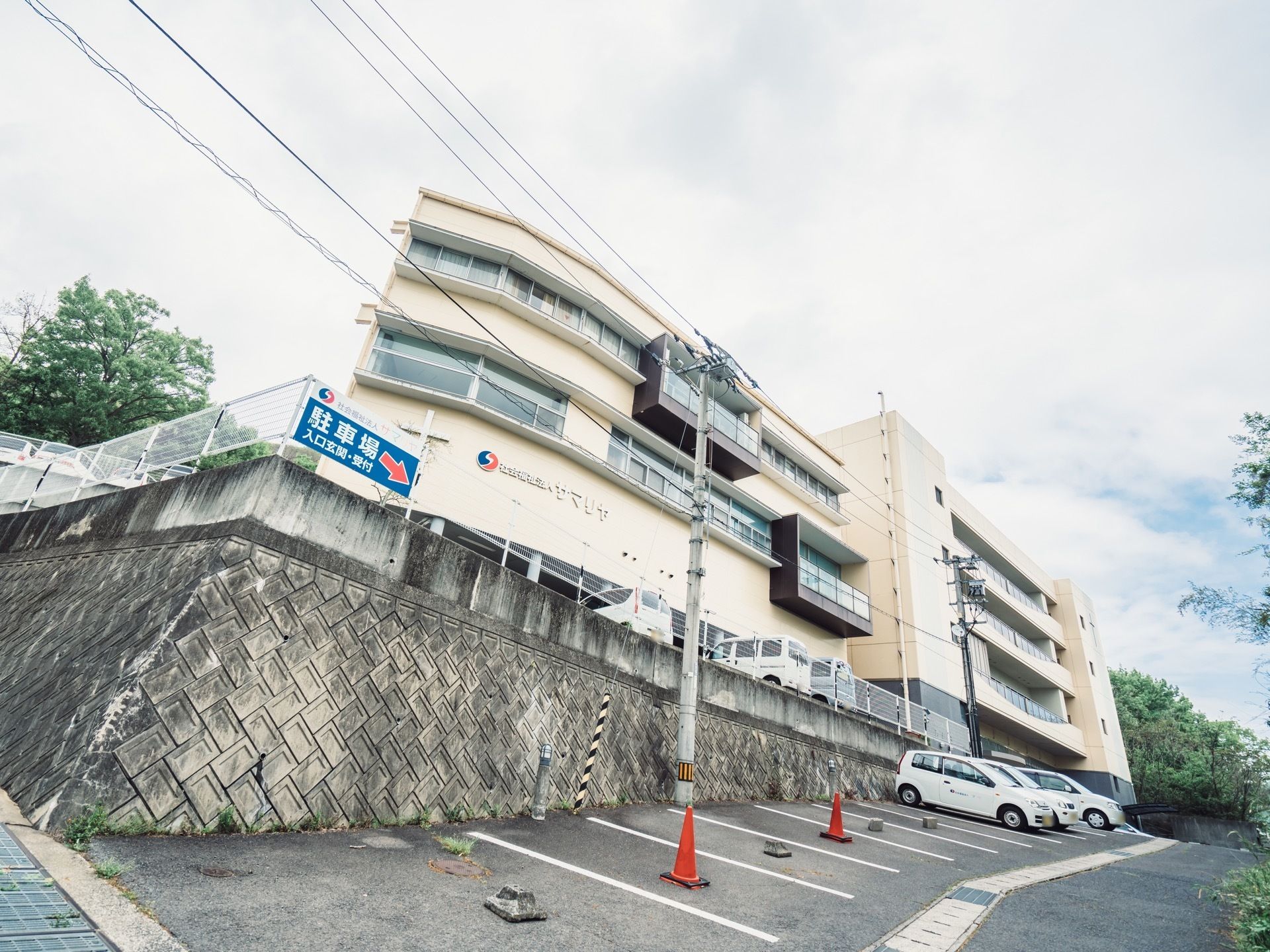 施設は白い３階建ての建物である。２階と３階には、バルコニーが設置されている。建物前に広い駐車場が設けられている。