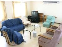 大小異なるデザインの椅子がテーブルを囲んだ共有スペースにはテレビもある。