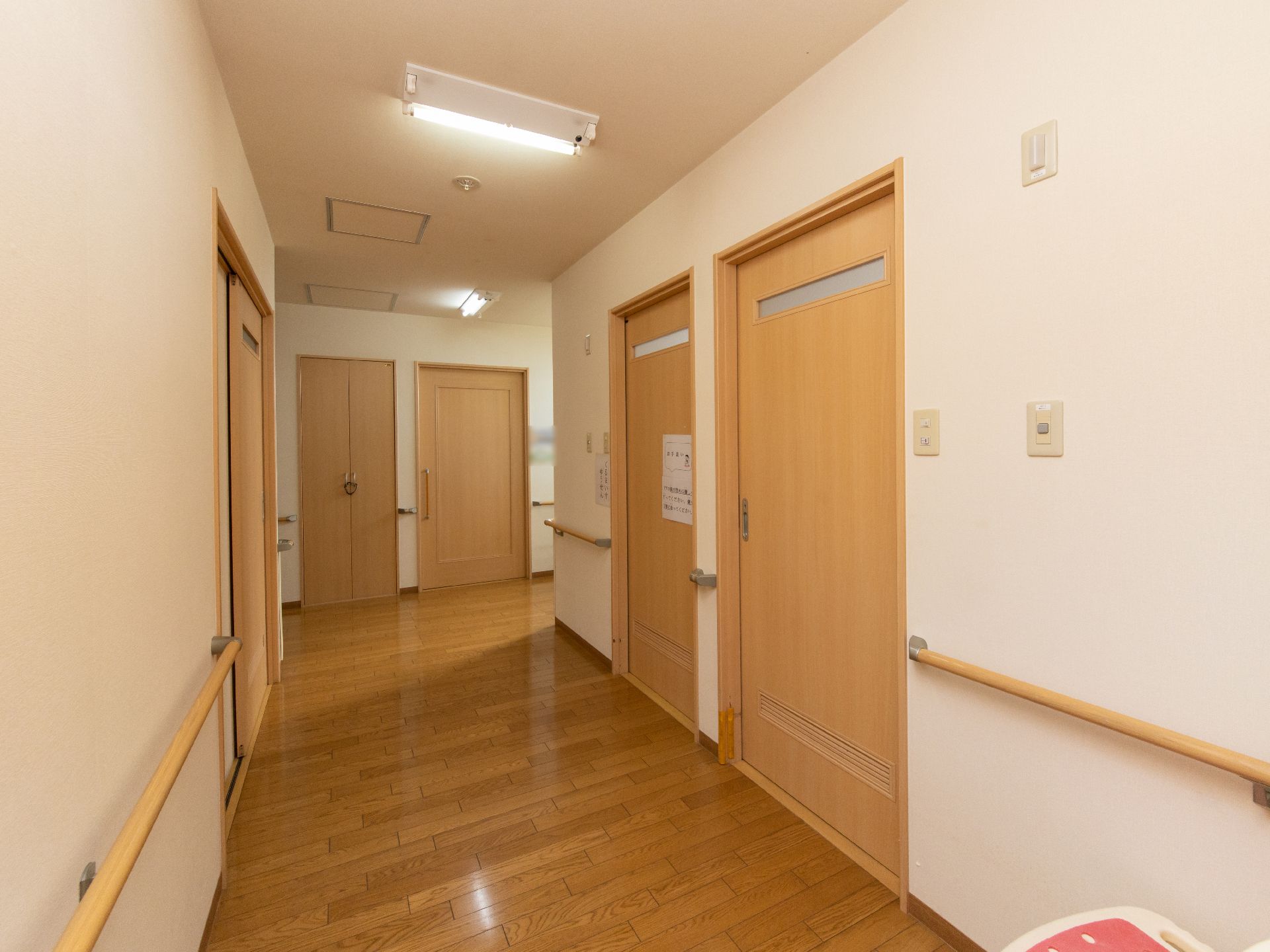 あたたかみある木目調を基調にした廊下である。明るい配色で開閉のしやすいスライド式扉や手すりが設置されている。