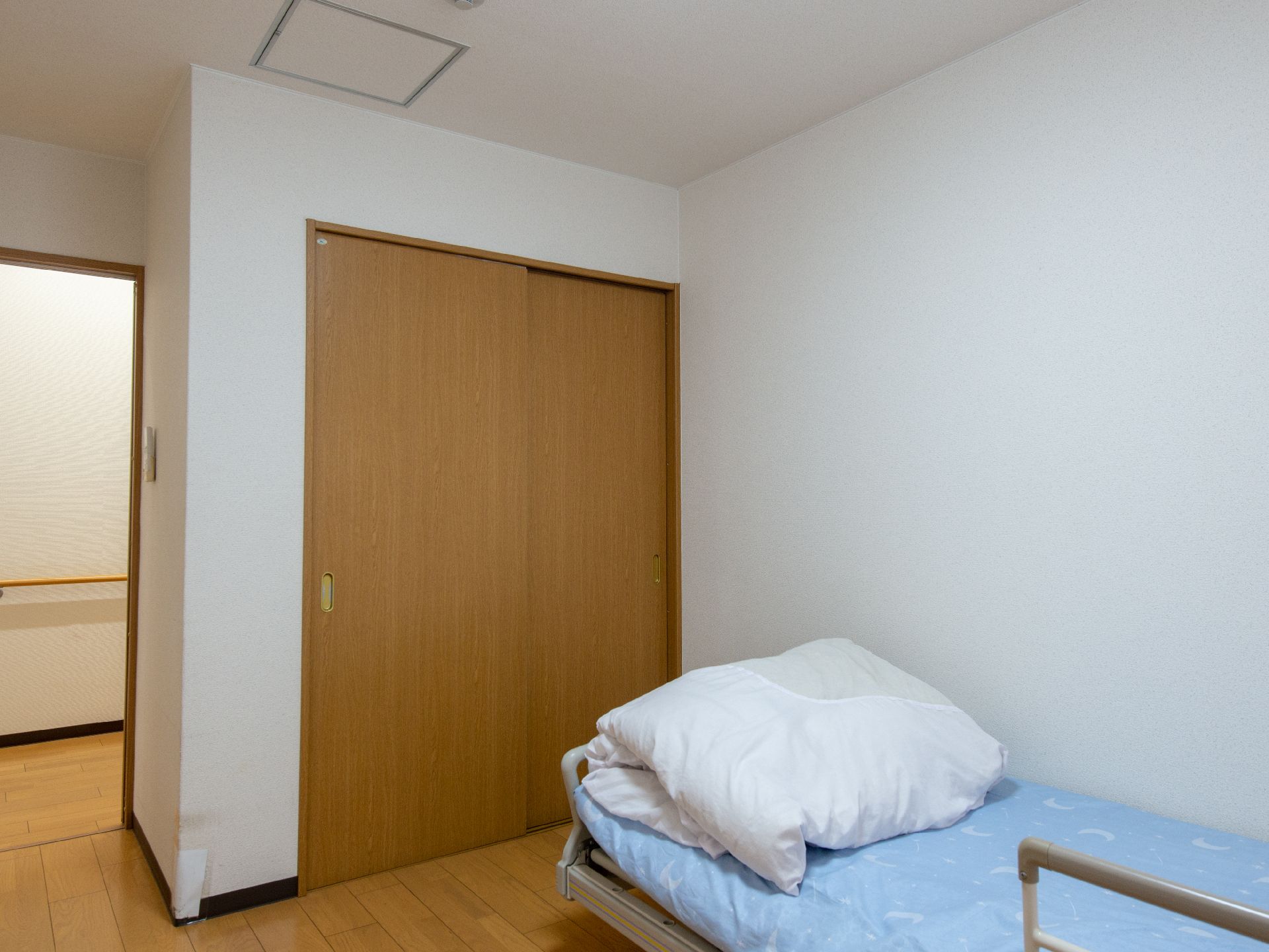 薬を飲もうとしている高齢女性と水の入ったコップを持ったエプロンを付けた若い女性スタッフ。