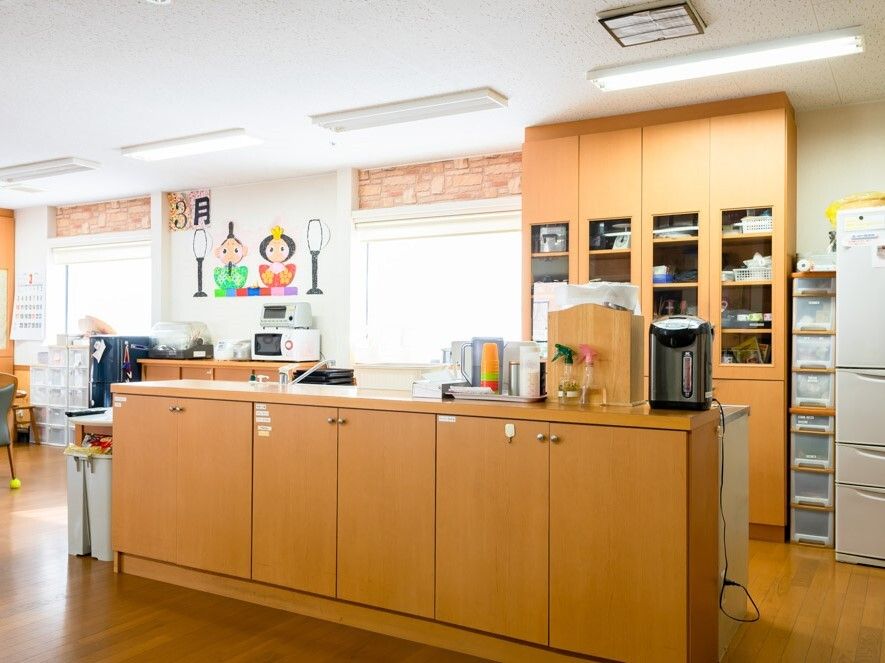 対面式のキッチンはカウンター部分が収納スペースになっていて、奥には大きなキッチンや冷蔵庫もある。