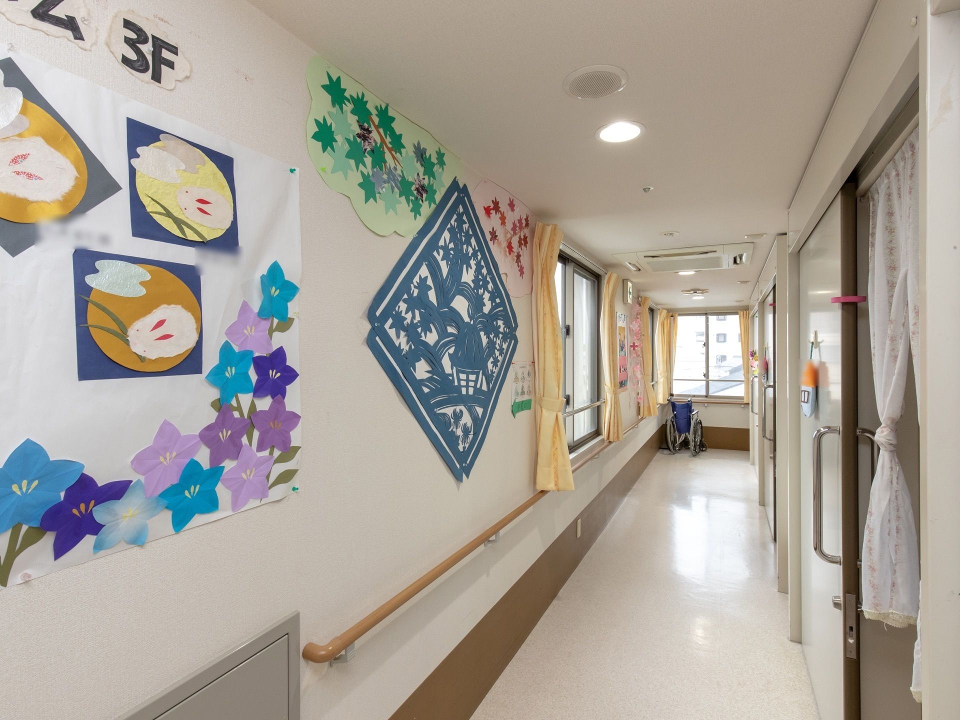日当たりの良い明るい廊下で、壁には手すりが設置されている。各居室の扉は、開閉のしやすいスライド式となっている。