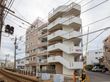 白を基調とした６階建ての大きなマンションのような外観のグループホームです。屋上部分には、転落防止のためフェンスが設置されている。