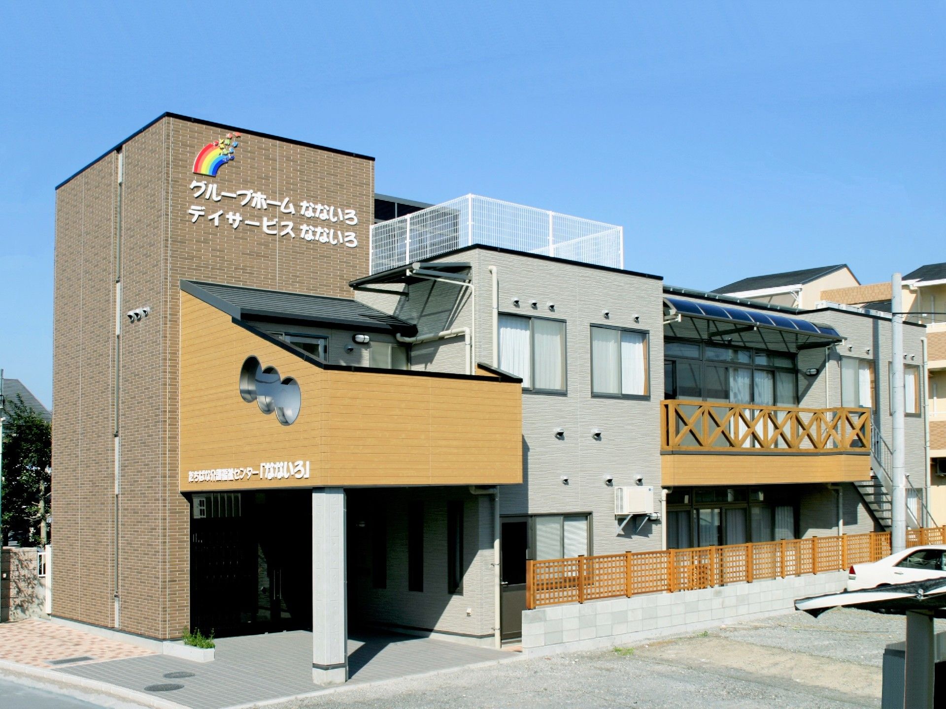 ブラウンを基調とした2階建ての建物。玄関部分には屋根が付き、2階部分にはベランダもある。