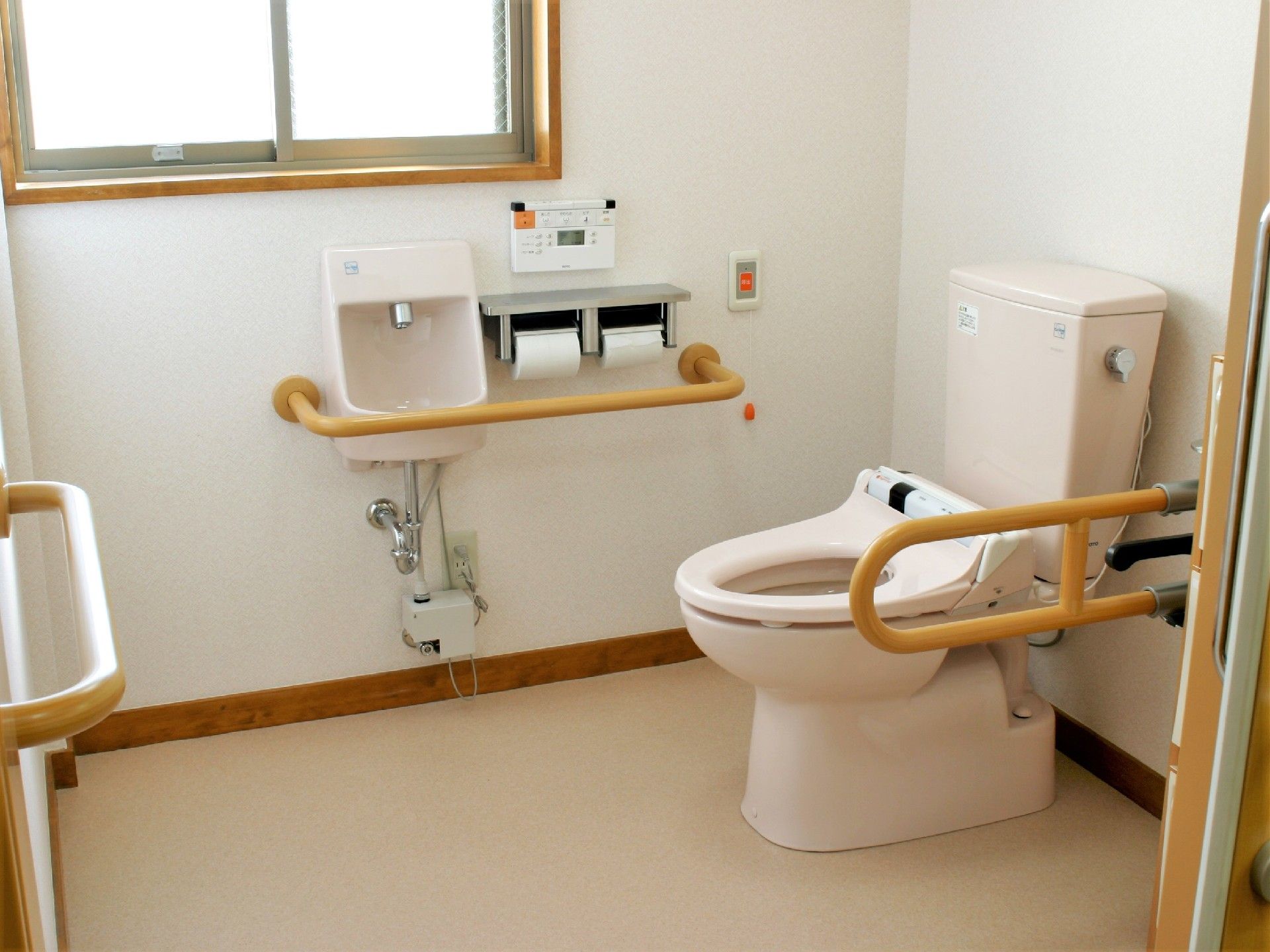手すり付きのトイレは淡いピンク色で手洗い場や呼び出しボタンも付いている。