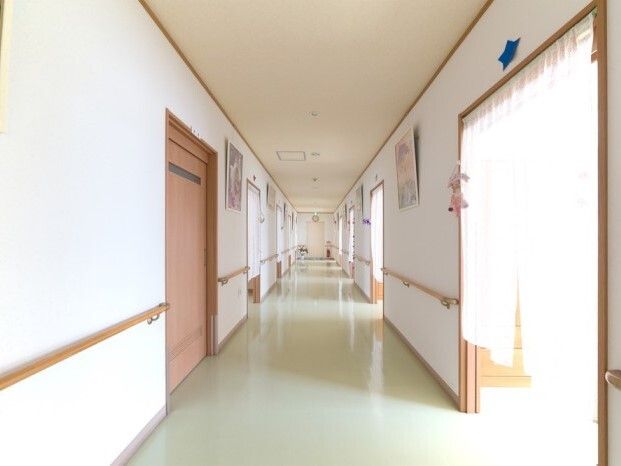 廊下に手すりがついている様子。両側に個室のドアがついている廊下