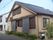 平屋建ての建物はブラウン系で、瓦屋根。緑が多く、一般の住宅のような外観。