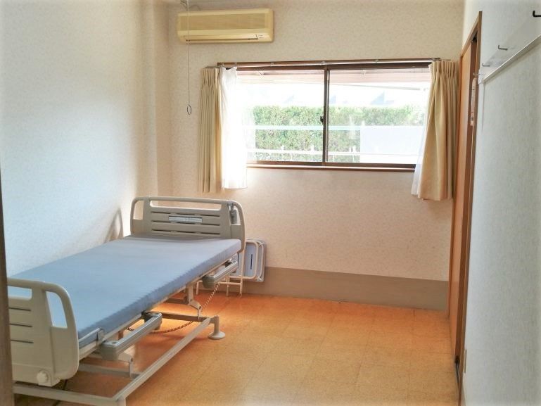 左側に介護用ベッドが置いてある小さな部屋の様子。エアコンと窓が付いた小さな部屋