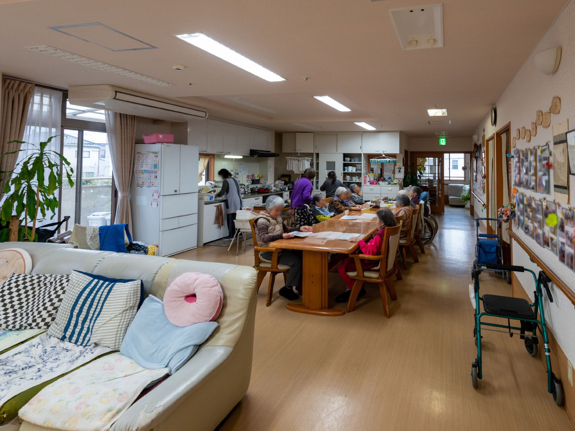 ブルーのポロシャツを着た若い女性スタッフに付き添われて屋外で過ごしている車いすの高齢女性。