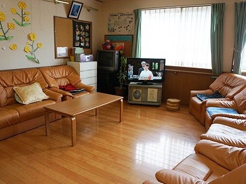 大きな窓が付いているリビングにはテレビやソファが置かれ、壁には手作りの花などが飾られている。