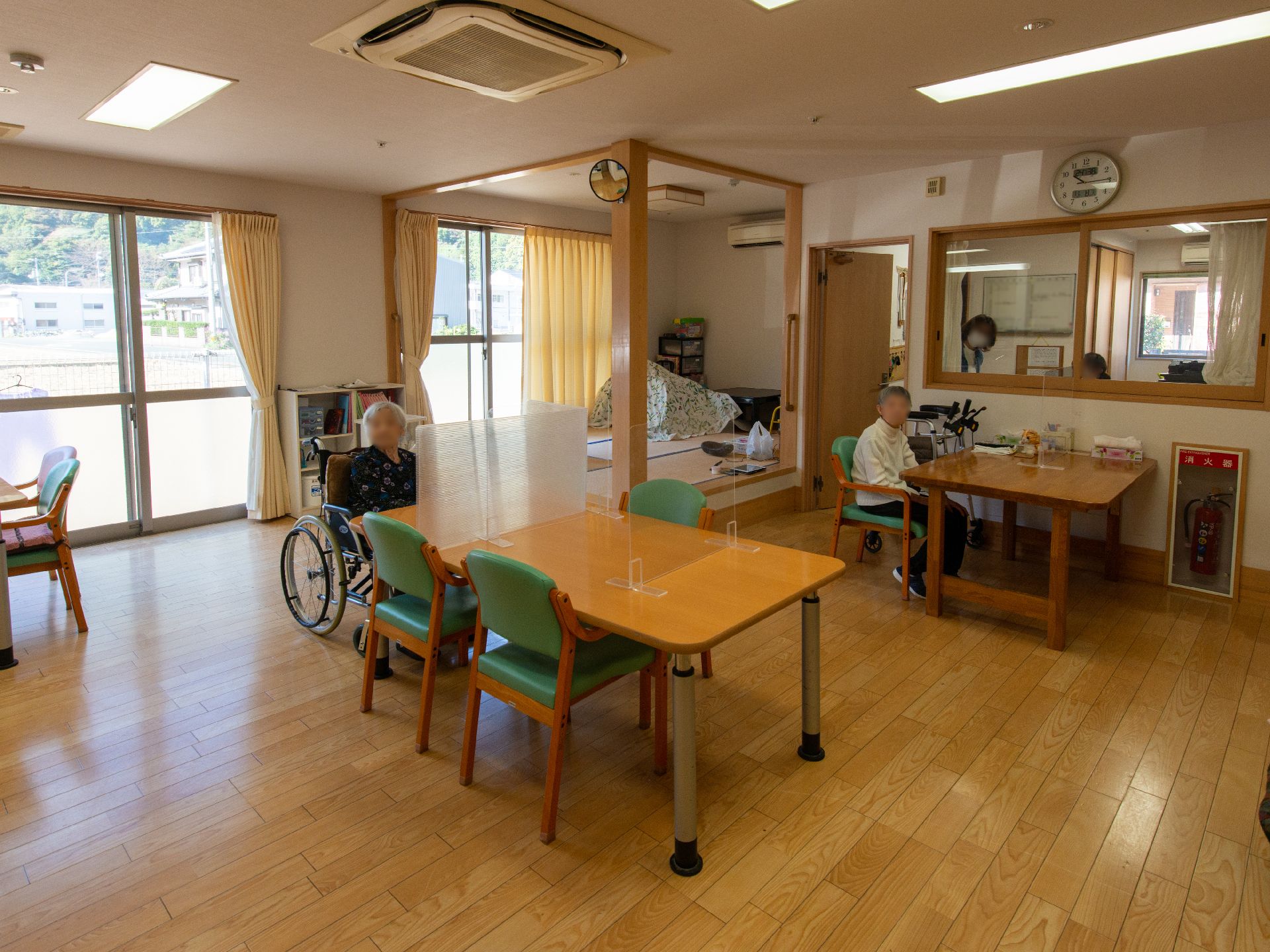 ベージュのソファを囲んで楽しそうに話している高齢女性たちの輪の中には白衣を着た女性スタッフもいる。