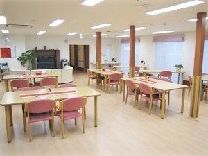 ピンクの椅子がセットされたダイニングテーブルが複数あり、奥にはソファがある。