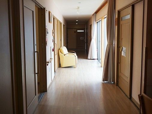 手すりが付いたまっすぐな廊下には黄色いソファが置かれ、カーテンが付いた大きな窓が付いている。