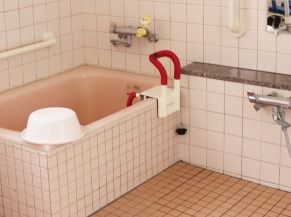 ピンクのタイルが貼られた明るい浴室には、一人ずつ入浴できる浴槽があり、手すりが設置されている。