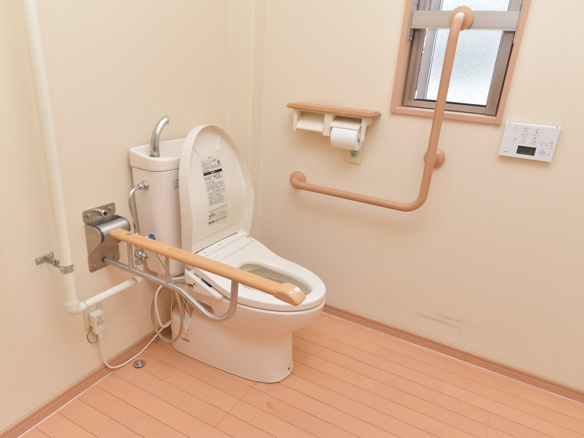 トイレは掃除が行き届いており、広々とした清潔感のある空間である。手すりは壁だけでなく、折りたたみ式も備え付けられている。