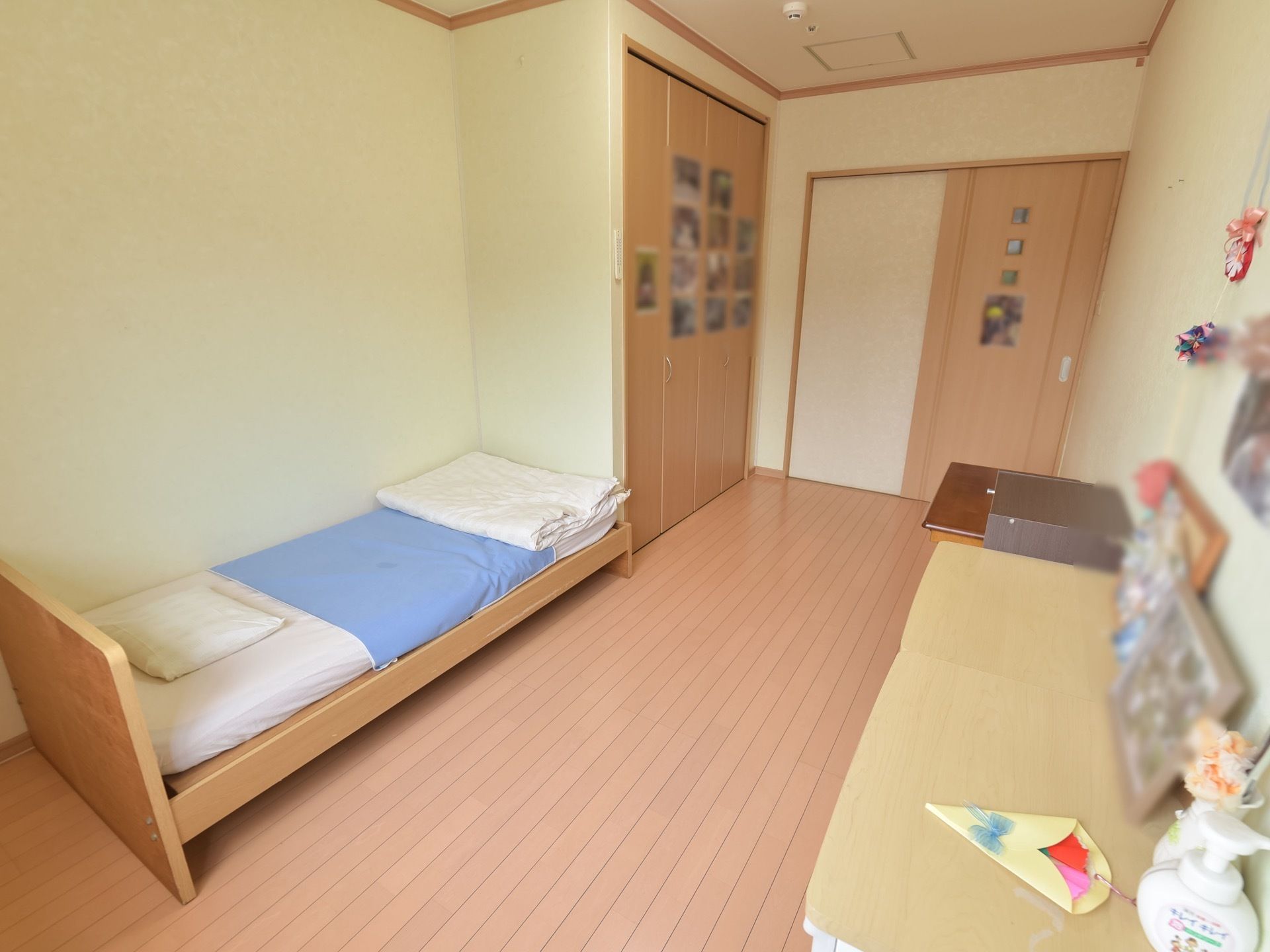 居室の壁や棚の上にはたくさんの写真が飾られている。介護用ベッドをはじめ、背丈の低いタンスや収納棚が置かれている。