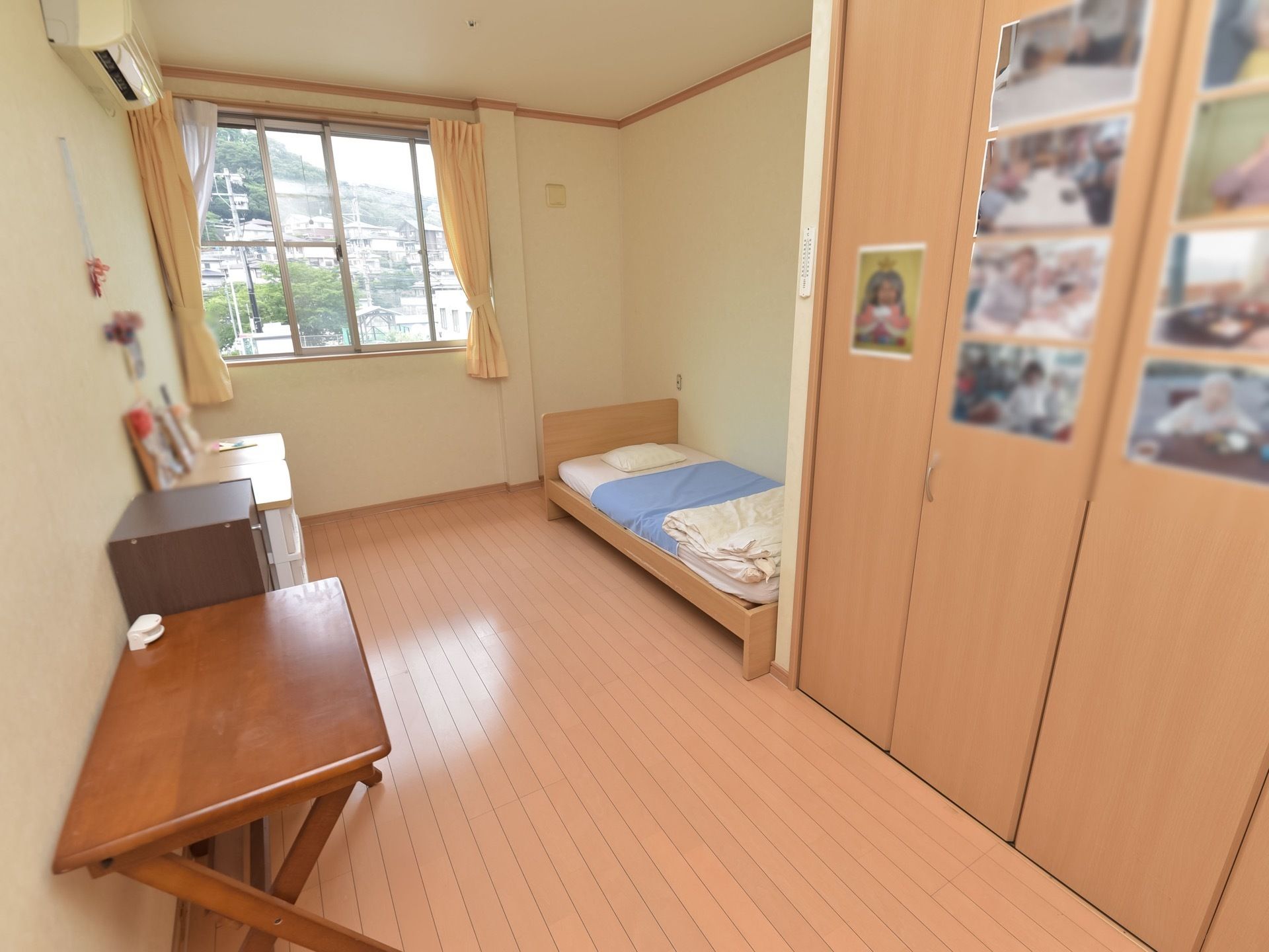 居室の窓からは外が見渡せる。住宅街には木々も多く、空を眺めることもできる。室内には写真がたくさん飾られている。