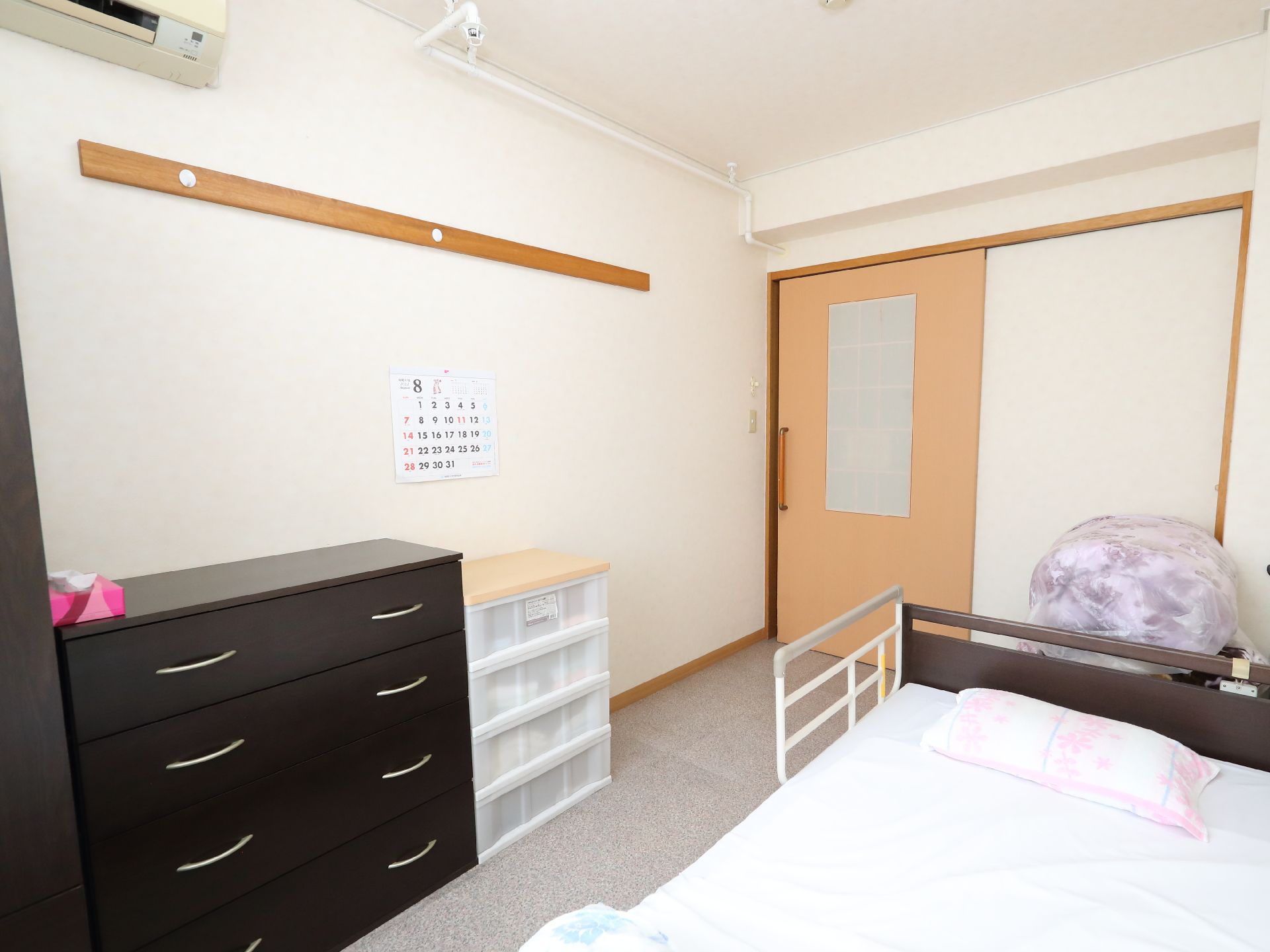 ベッドと黒い棚が置かれた白い壁の部屋