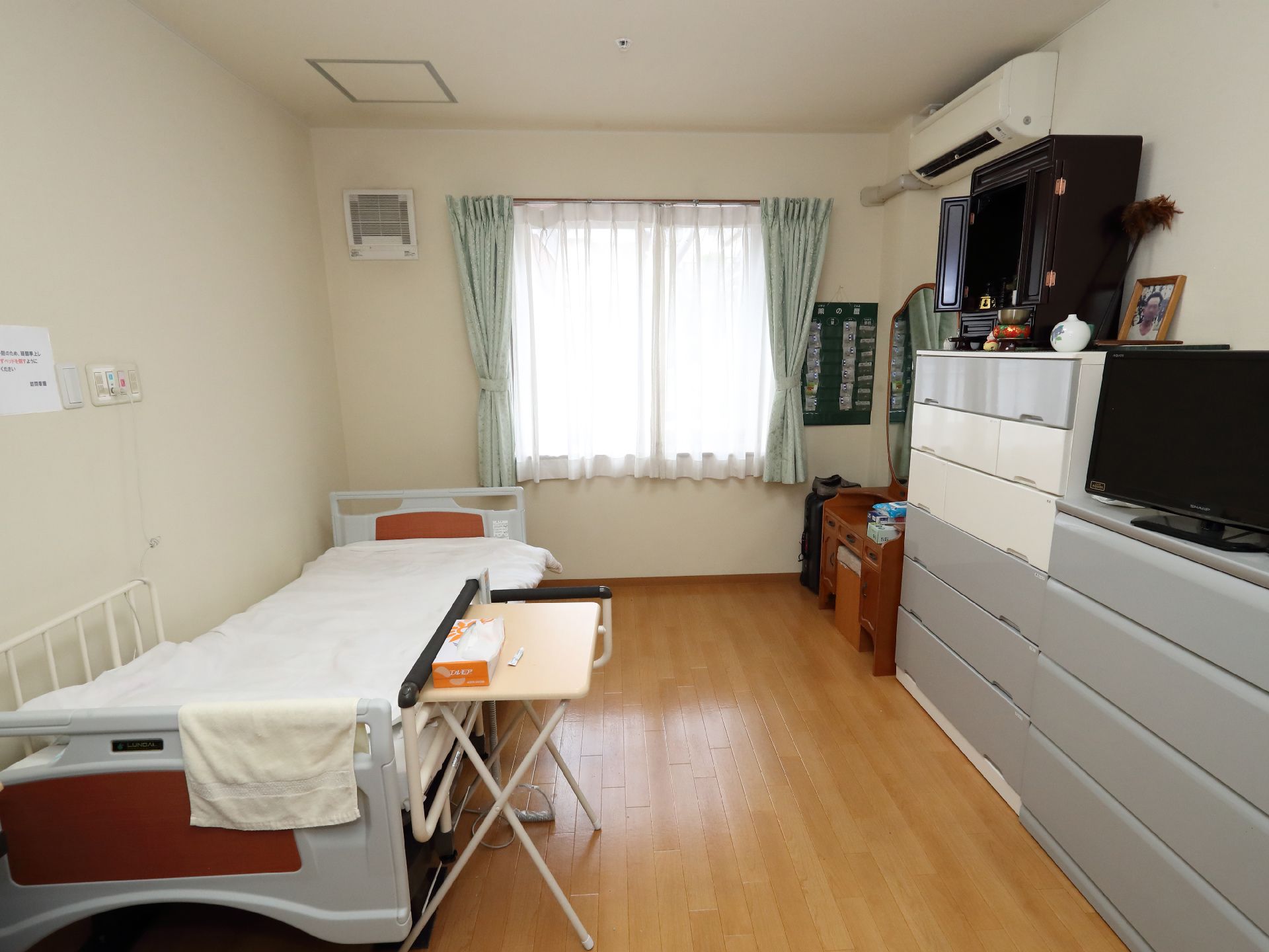 ベッドと灰色の棚が白い壁沿いに配置された部屋